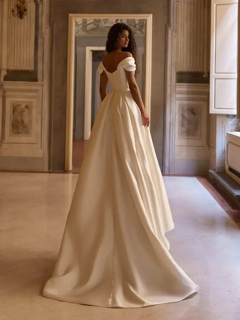 model is wearing an off the shoulder a-line bridal gown
